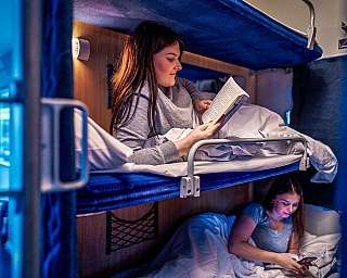 Zwei Frauen lesen in einem Liegewagen-Abteil im Nachtzug.