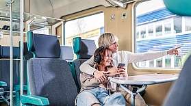 Ein junges Paar sitz im Großraum-Abteil im Reisezugwagen