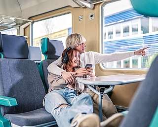 Ein junges Paar sitz im Großraum-Abteil im Reisezugwagen